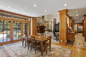 Dining area with healthy amount of natural light, french doors, a large fireplace, decorative columns, and recessed lighting