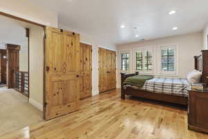 Bedroom with recessed lighting, multiple closets, light wood finished floors, and baseboards