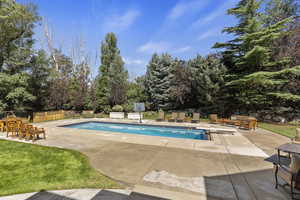 Outdoor pool with a patio area, view of scattered trees, a diving board, and an outdoor hangout area