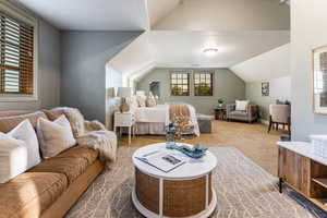 Living area with vaulted ceiling, carpet flooring, and a textured ceiling