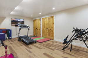 Workout area with wood finished floors, baseboards, and recessed lighting