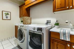 Laundry room with light tile patterned floors, cabinet space, and washer and dryer