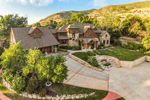 View of front of home featuring stone siding, a mountain view, a front lawn, and covered porch