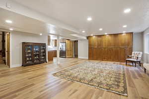 Sitting room with recessed lighting, light wood-style floors, baseboards, and stairs