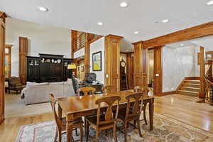Dining space featuring light wood-style flooring, decorative columns, recessed lighting, stairs, and a textured ceiling