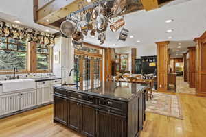 Kitchen featuring a sink, dark countertops, decorative columns, light wood finished floors, and recessed lighting