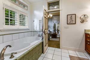 Bathroom with vanity, light tile patterned floors, a bath, and a chandelier