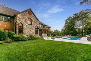 View of green lawn featuring an outdoor pool and a patio area