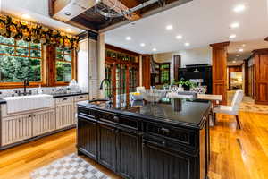 Kitchen with dark cabinets, recessed lighting, light wood-style floors, a center island with sink, and tasteful backsplash