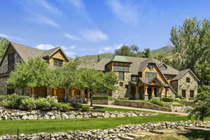 Shingle-style home featuring stone siding, a front lawn, and a mountain view
