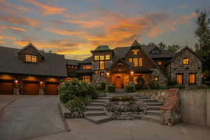 View of front of house with concrete driveway, stone siding, roof with shingles, and a garage