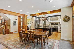 Dining room with a textured ceiling, baseboards, recessed lighting, light wood-type flooring, and stairway