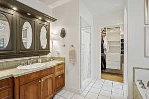 Bathroom featuring tile patterned flooring, vanity, a walk in closet, a shower with shower curtain, and baseboards
