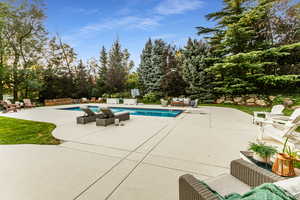 Outdoor pool featuring a patio, an outdoor hangout area, and view of wooded area