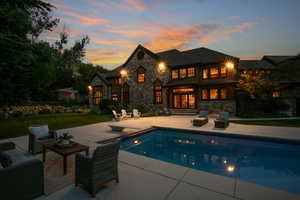 Back of house featuring a lawn, stone siding, an outdoor hangout area, a patio area, and an outdoor pool