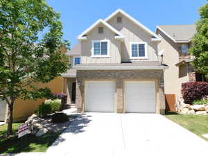 View of front of home featuring board and batten siding, an attached garage, concrete driveway, and brick siding