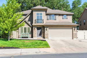 View of front of home featuring a gate, stone siding, a shingled roof, an attached garage, and concrete driveway