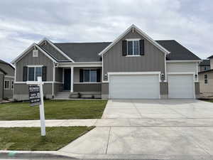 Craftsman-style home with board and batten siding, a shingled roof, concrete driveway, and a front lawn