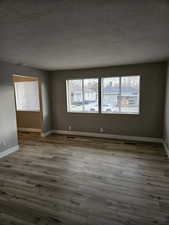 Empty room featuring hardwood / wood-style flooring, a healthy amount of sunlight, and a textured ceiling