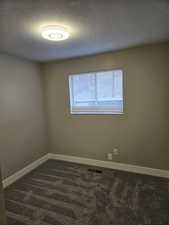 Carpeted empty room featuring a textured ceiling