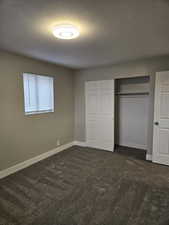 Unfurnished bedroom with carpet floors, a textured ceiling, and a closet