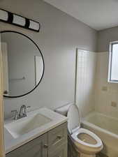 Full bathroom with toilet, vanity, and tiled shower / bath
