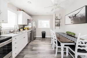 Kitchen with light countertops, white cabinets, wood finished floors, recessed lighting, and appliances with stainless steel finishes