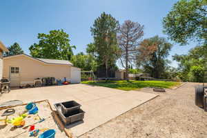 View of patio / terrace featuring a trampoline, a fire pit, grilling area, and a shed