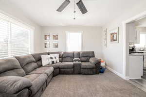 Living area featuring light colored carpet and a ceiling fan