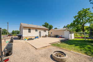 Back of house with a trampoline, an outbuilding, and a patio