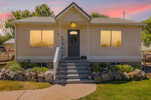 Bungalow-style home with roof with shingles and a front lawn