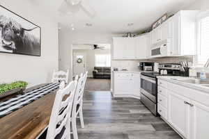 Kitchen with stainless steel electric range, white microwave, decorative backsplash, white cabinets, and recessed lighting