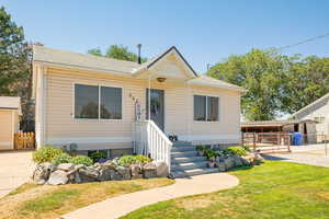 View of front of home with a shingled roof, a gate, and an outbuilding