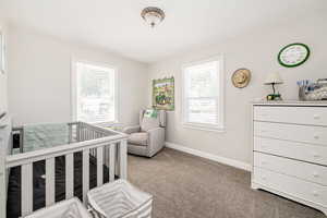 Carpeted bedroom with baseboards and a nursery area