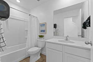 MAIN FLOOR: Full bathroom with vanity, shower / tub combo with curtain, and wood finished floors