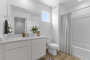 Ensuite bathroom with wood finished floors, vanity, and shower / bath combo and walk in closet