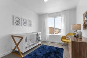 Carpeted bedroom featuring baseboards and a crib
