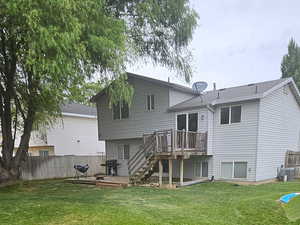 View of grassy yard featuring stairway and a wooden deck