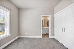 Unfurnished bedroom featuring carpet, connected bathroom, and a closet