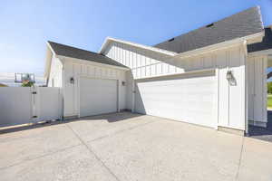 View of side of property with roof with shingles, board and batten siding, concrete driveway, and a garage
