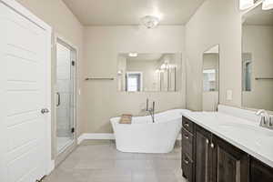 Full bathroom featuring a stall shower, vanity, a soaking tub, and tile patterned flooring