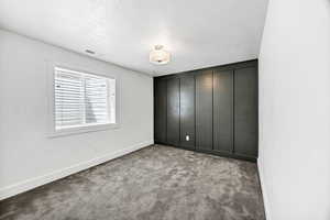Unfurnished bedroom with a textured ceiling and carpet floors
