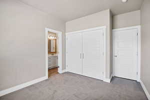 Unfurnished bedroom with carpet, a closet, and ensuite bath