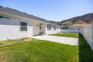 Rear view of property featuring a patio area, a fenced backyard, a mountain view, and roof with shingles