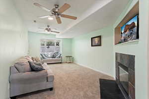 Carpeted living room with a textured ceiling, a fireplace, and ceiling fan
