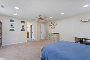 Bedroom with light colored carpet, recessed lighting, a textured ceiling, a ceiling fan, and ensuite bathroom