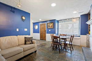 Dining space featuring stone tile flooring, a textured ceiling, track lighting, and recessed lighting