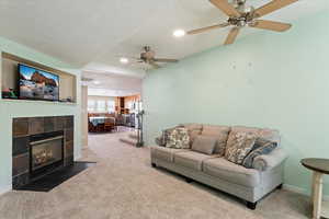 Living area featuring carpet floors, a textured ceiling, a fireplace, recessed lighting, and a ceiling fan