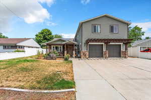 View of front of home with stone siding, a porch, an attached garage, and driveway