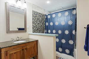 Full bathroom featuring vanity, shower / tub combo, and a textured ceiling